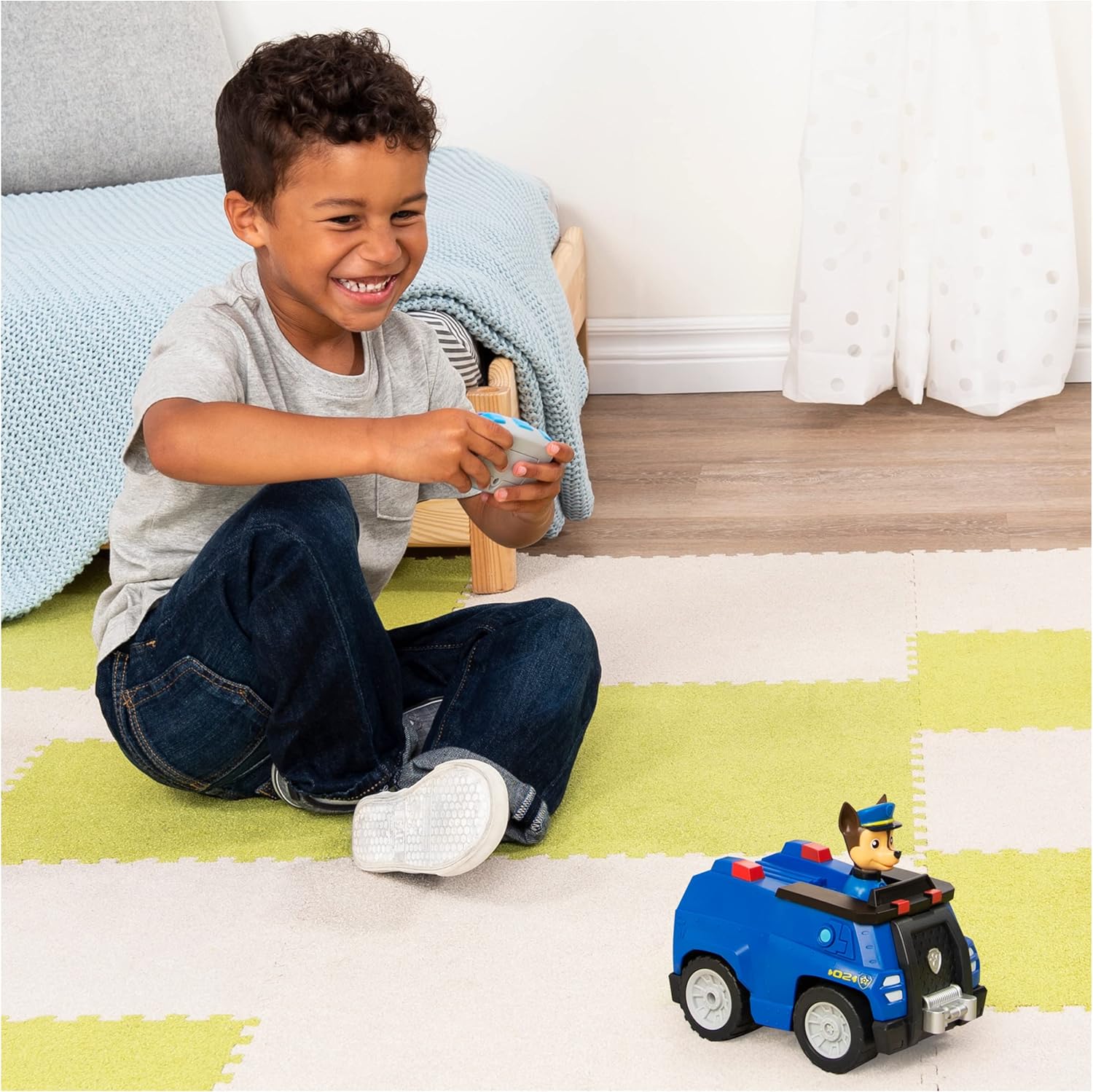 Garoto a brincar com carrinho policial azul e figura de cão de brinquedo