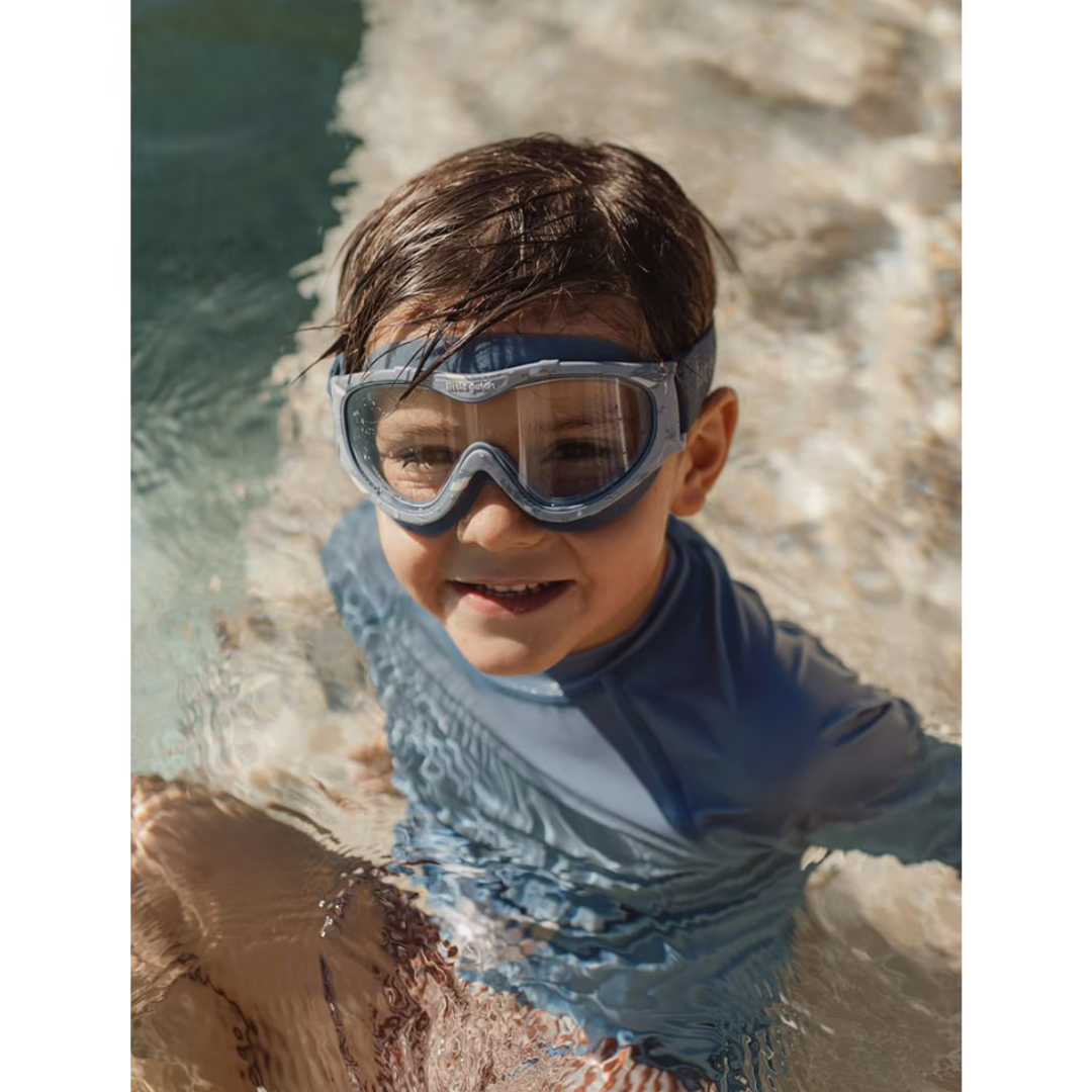 Criança a usar fato de banho azul e óculos de natação em piscina