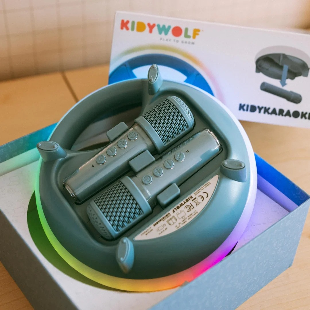 Microfones cinza num suporte iluminado com LEDs coloridos em caixa com texto KidyWolf
