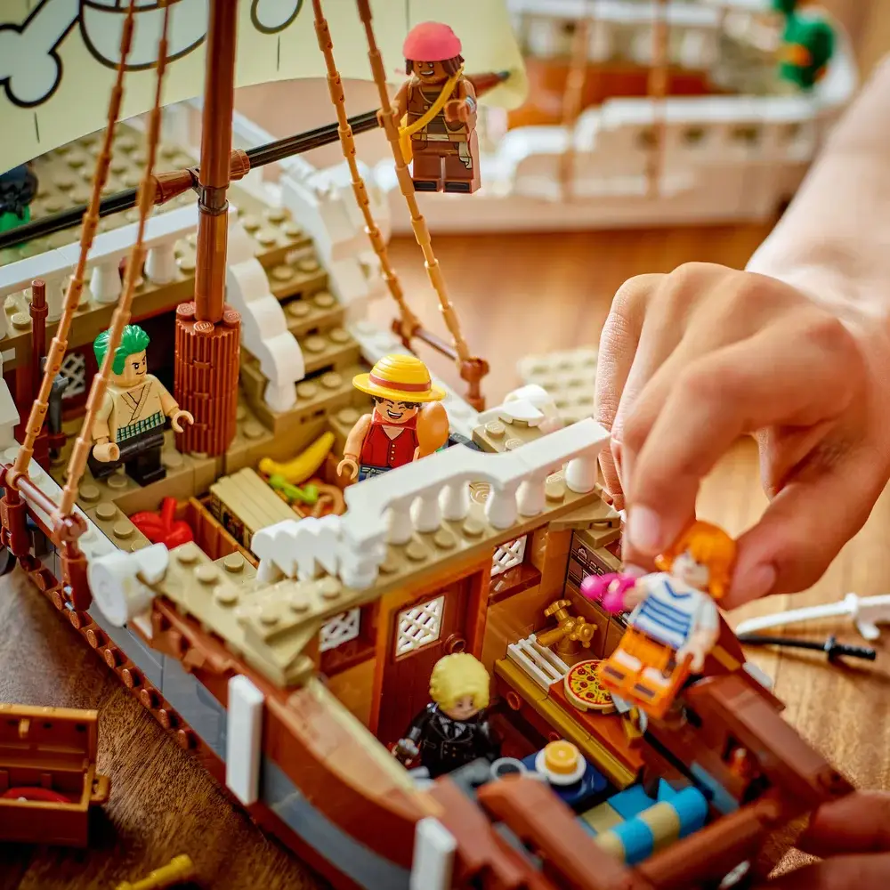 Barco de brinquedo de construção com várias figuras em miniatura coloridas e mãos humanas interagindo