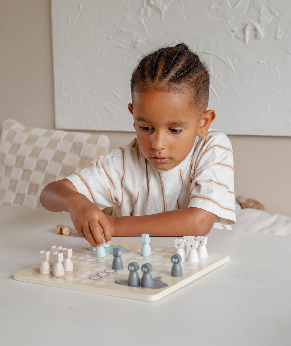 Criança a jogar jogo de tabuleiro em madeira com peças coloridas pastel.