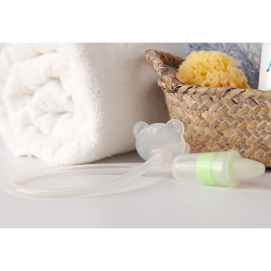 Fralda branca, esponja amarela em cesto, aspirador nasal de bebé