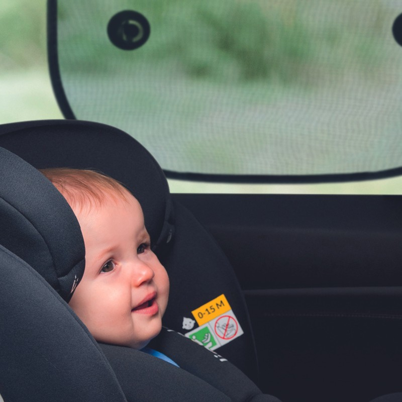 Bebé numa cadeira auto preta dentro de um carro