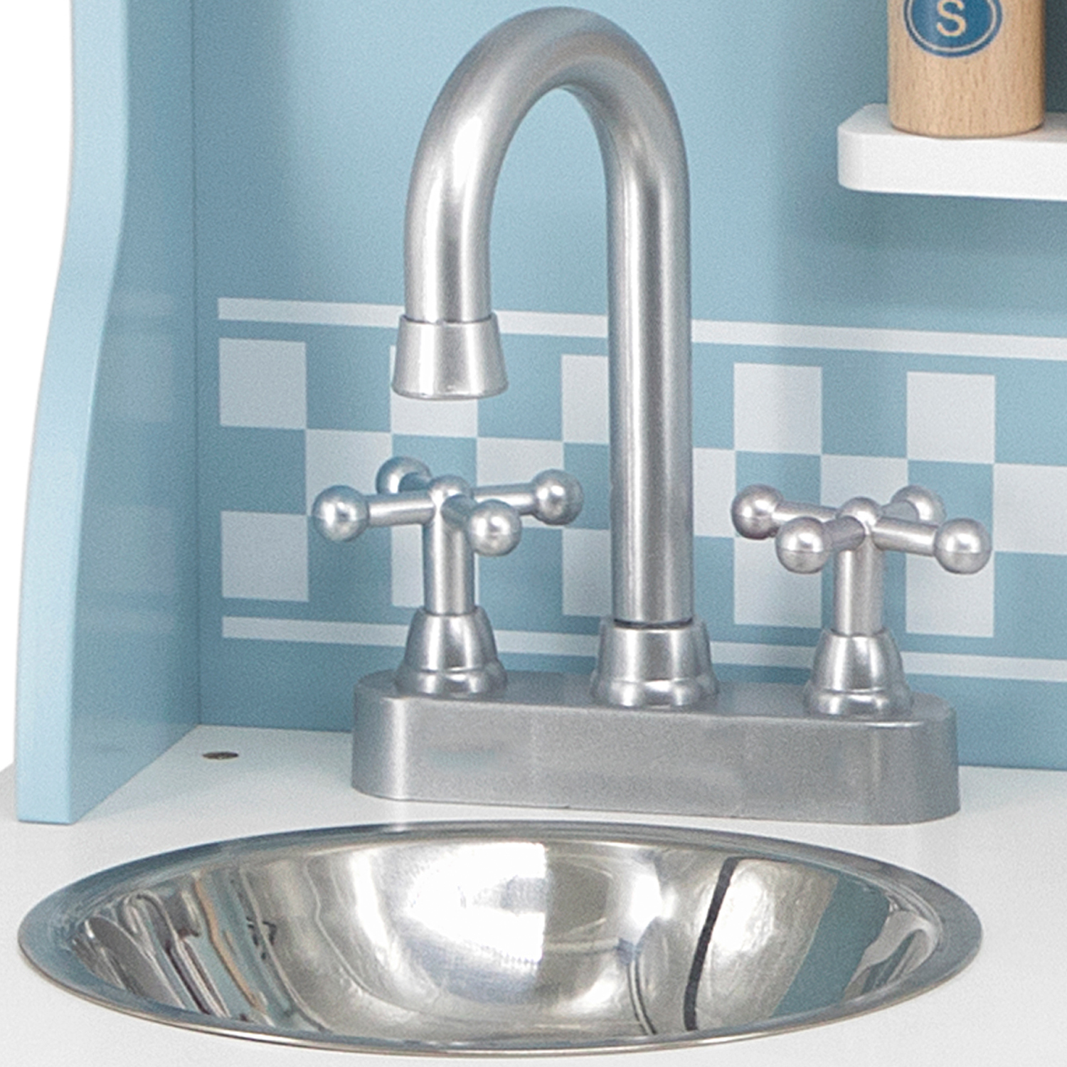 Torneira e bacia de metal prateado numa bancada branca com fundo azul quadriculado.