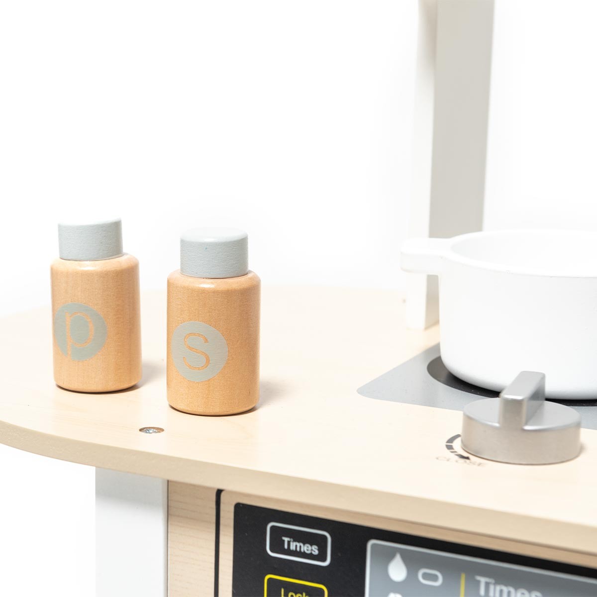 Conjunto de potes de madeira com letras 'p' e 's' numa superfície de madeira clara ao lado de um prato branco