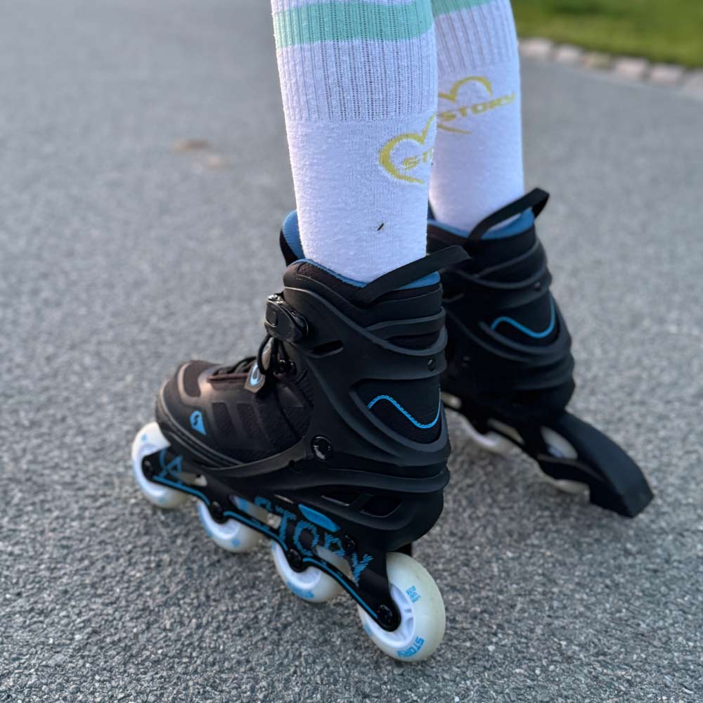 Patins em linha pretos com detalhes azuis e rodas brancas usados em asfalto