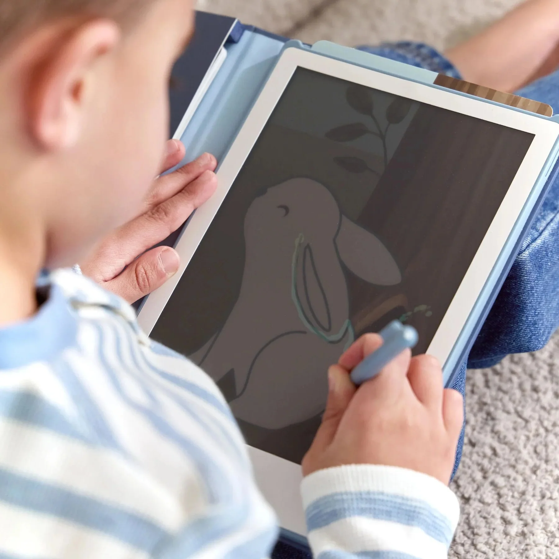 Tablet com ilustração de coelho na mão de criança com camisola às riscas azuis