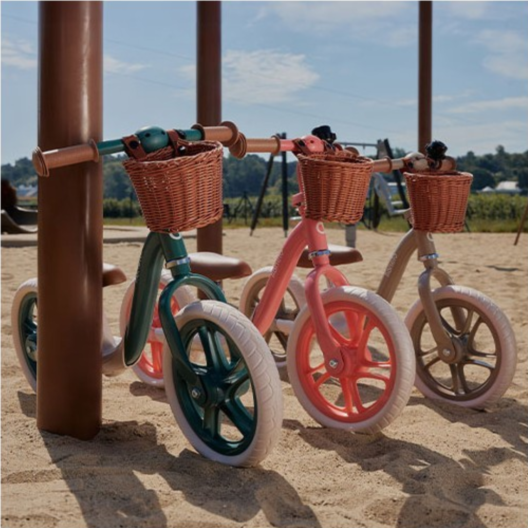 Três bicicletas sem pedais coloridas com cestos de vime em areia