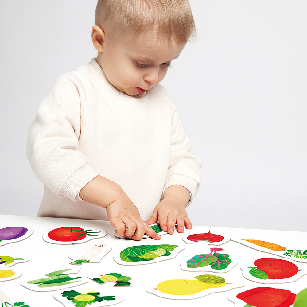 Criança joga com puzzle de legumes e frutas coloridas