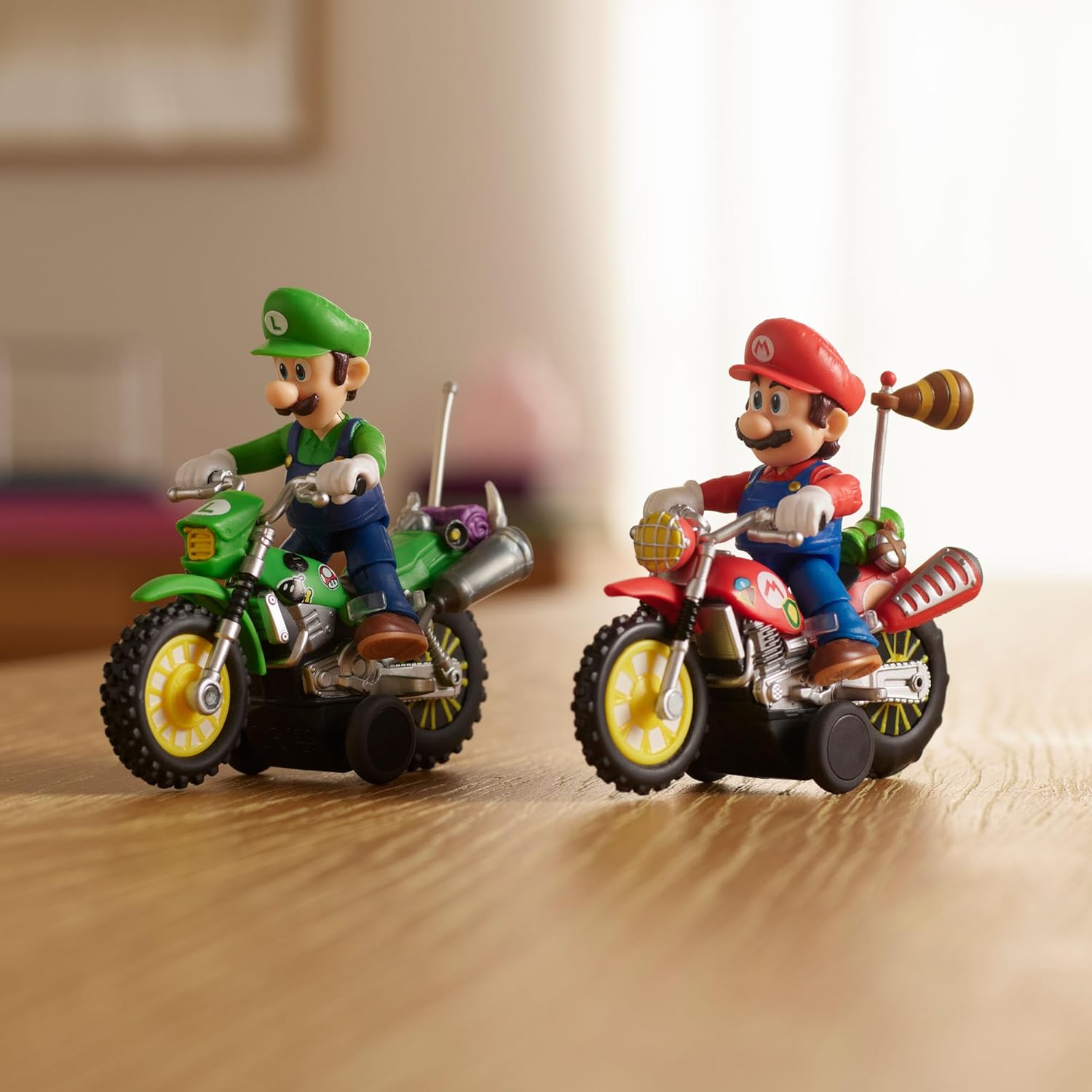 Figuras de Mario e Luigi em motos de brinquedo vermelha e verde numa mesa de madeira.