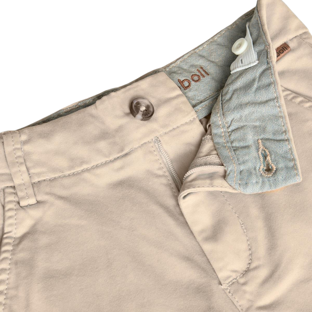 Calças beige com fecho aberto mostrando interior cinza e texto bordado boll