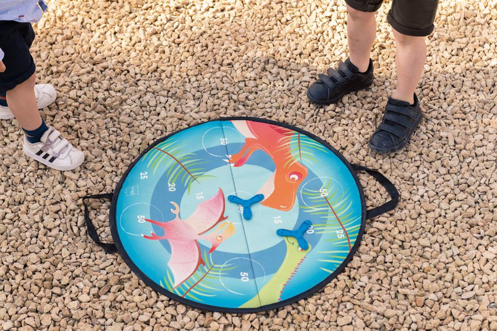 Jogo de lançamento com alvo redondo colorido e crianças a jogar em chão de pedras