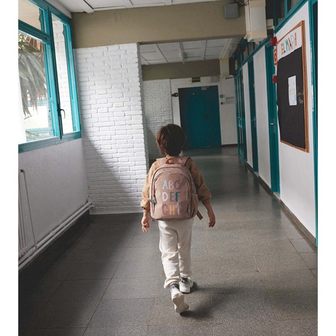 Criança com mochila rosa clara num corredor escolar