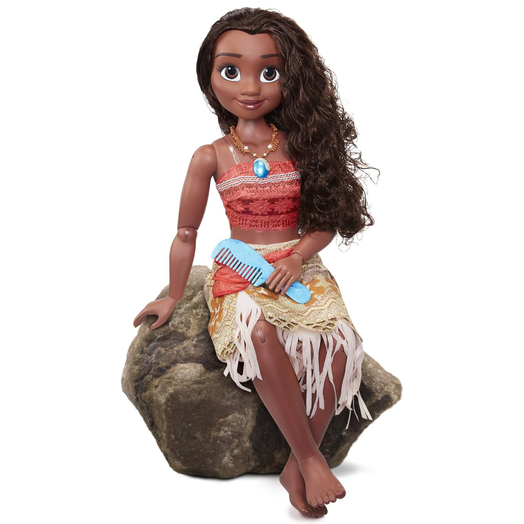 Boneca com cabelo encaracolado e roupa colorida sentada numa pedra