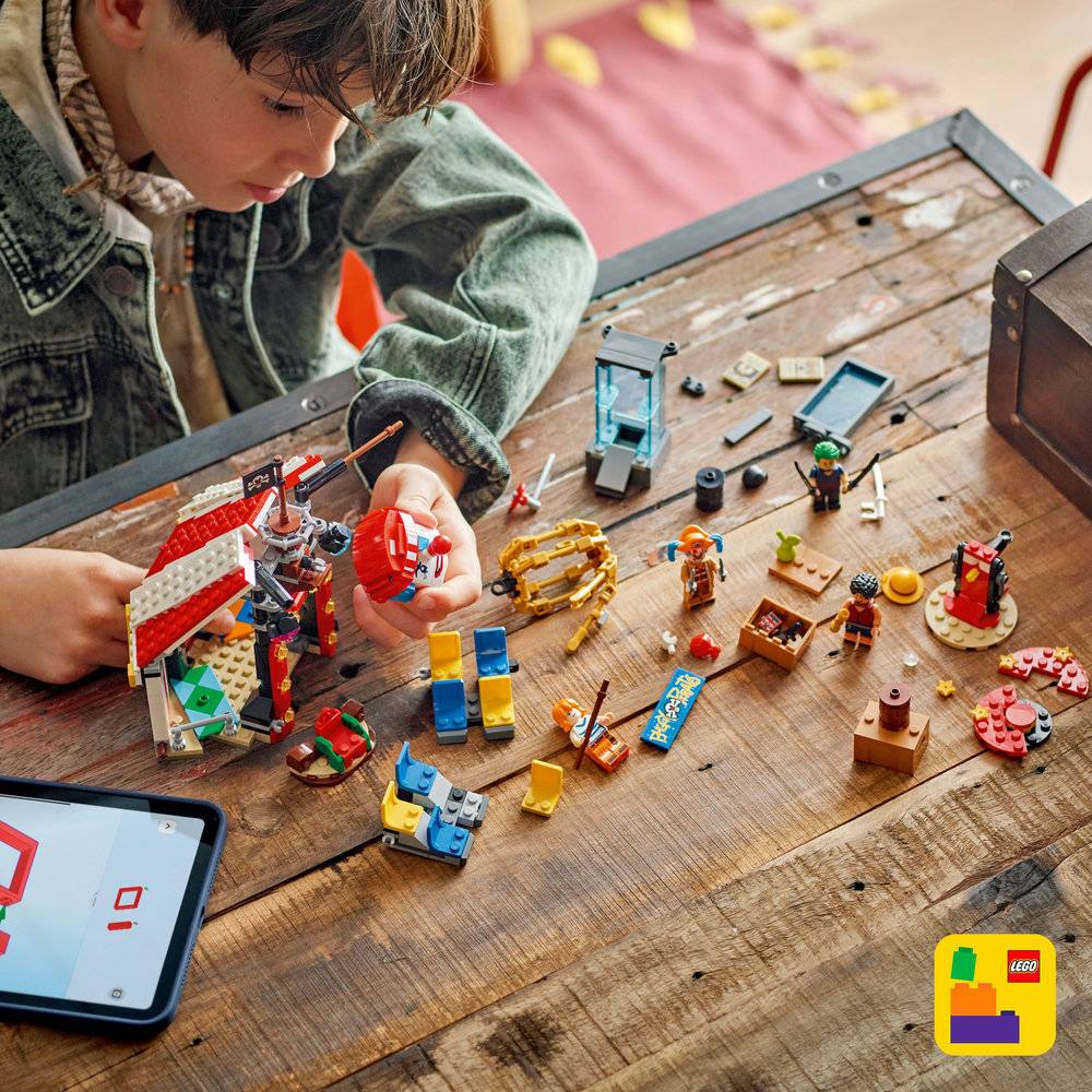 Conjunto de brinquedo LEGO com várias peças e figuras numa mesa de madeira com tablet ao lado e logótipo LEGO