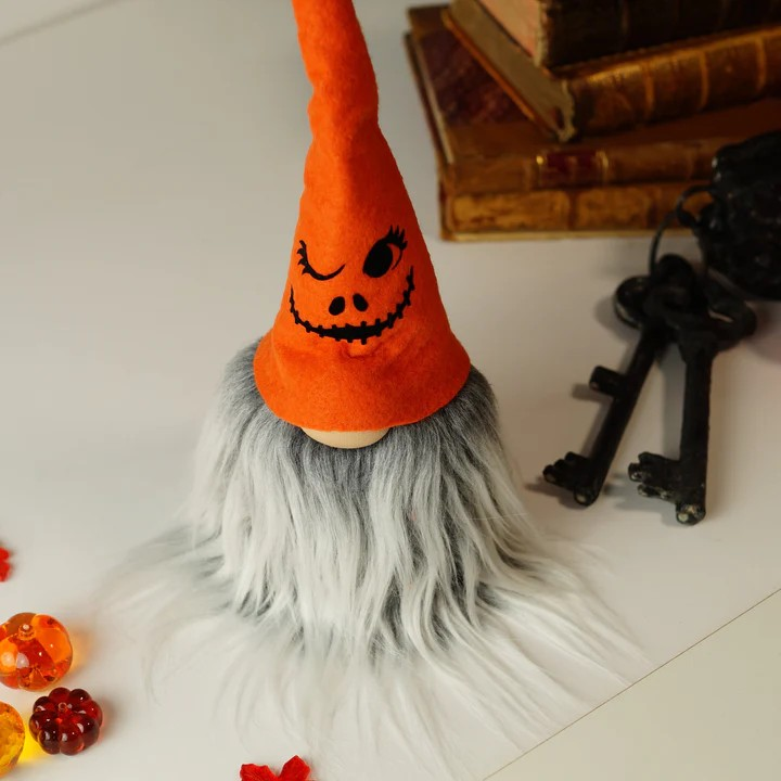 Figura decorativa com chapéu laranja e cabelo cinza sobre mesa branca