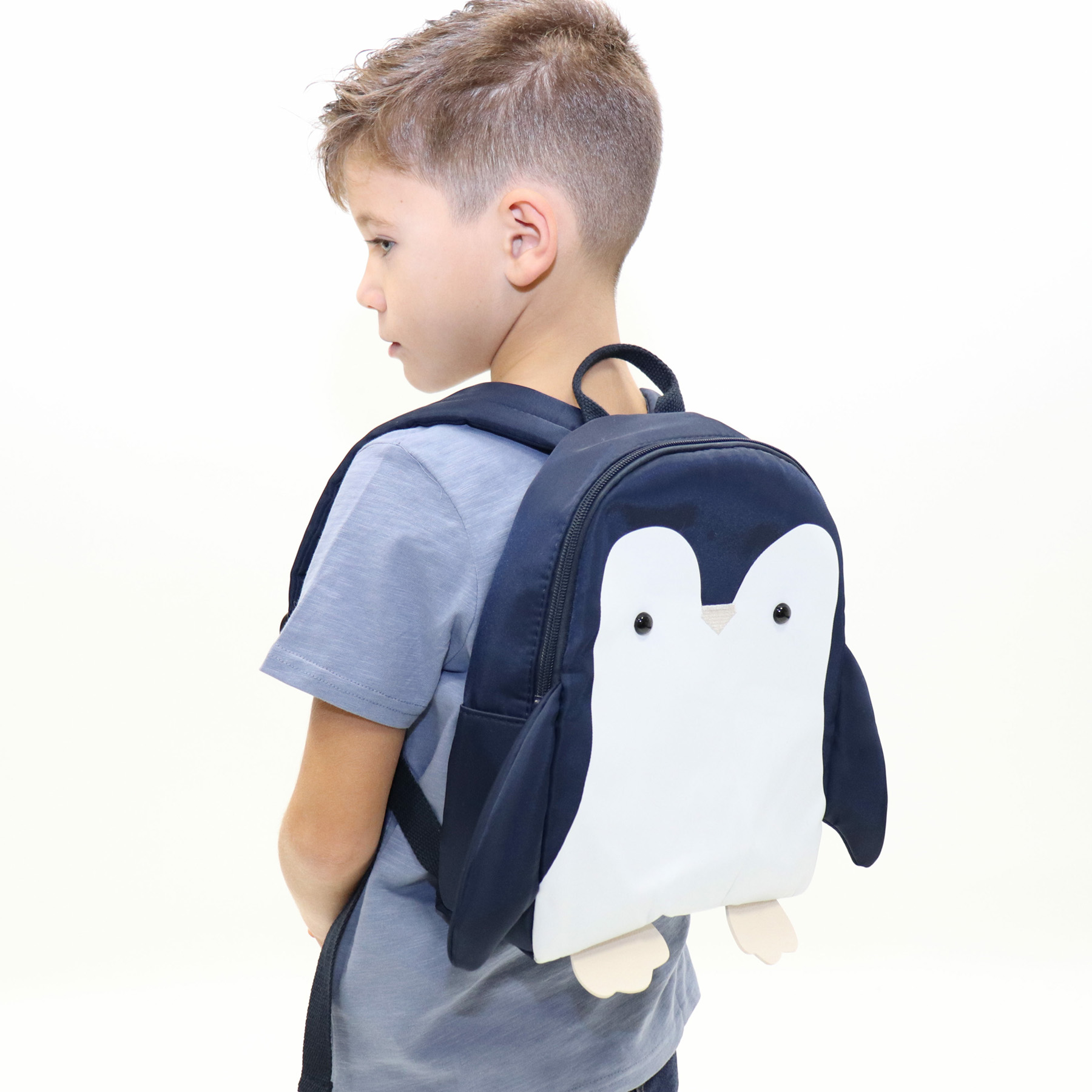Mochila infantil azul com pinguim branco usada por criança