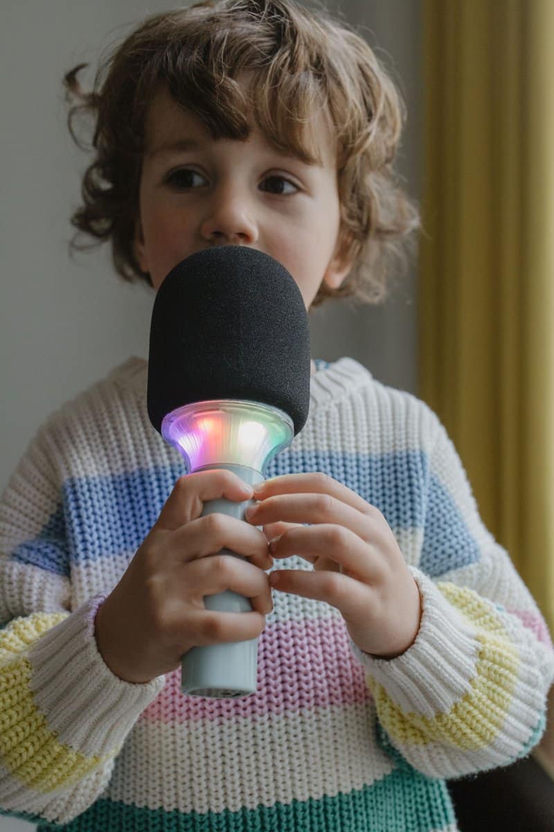 Criança com microfone LED colorido vestindo camisola de malha colorida