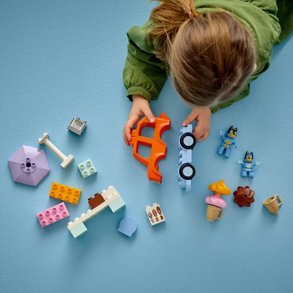 Criança brinca com blocos de construção coloridos no chão azul