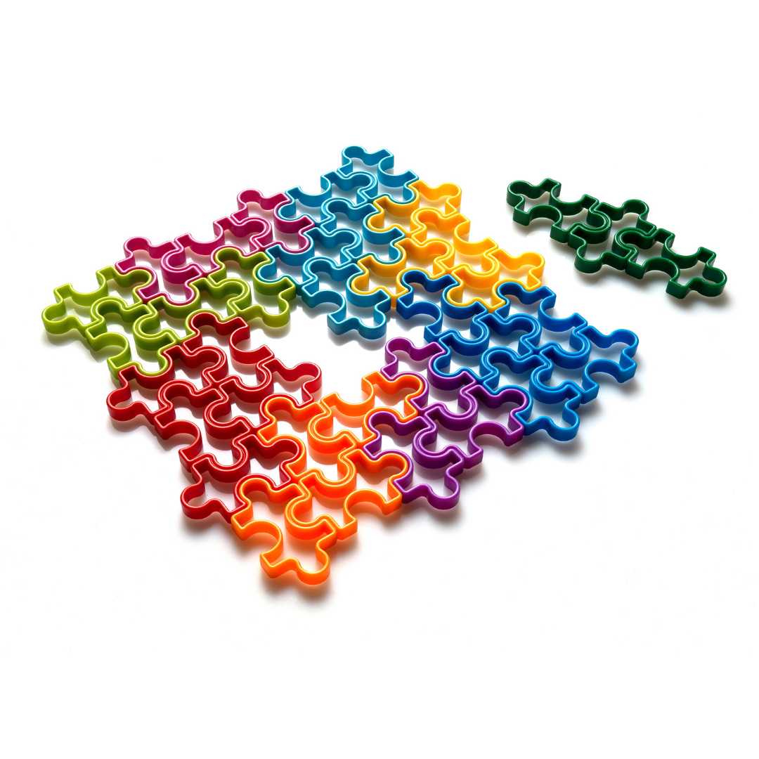 Corta-massas de plástico em forma de puzzle, coloridos, sobre fundo branco.