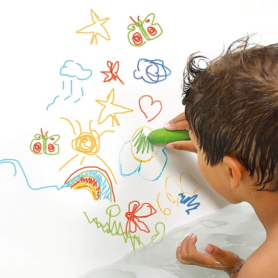 Criança a desenhar com marcador verde em superfície branca com desenhos coloridos variados