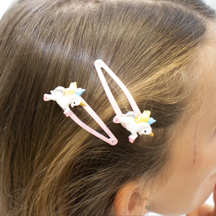Par de molas de cabelo com unicórnios coloridos em cabelo castanho