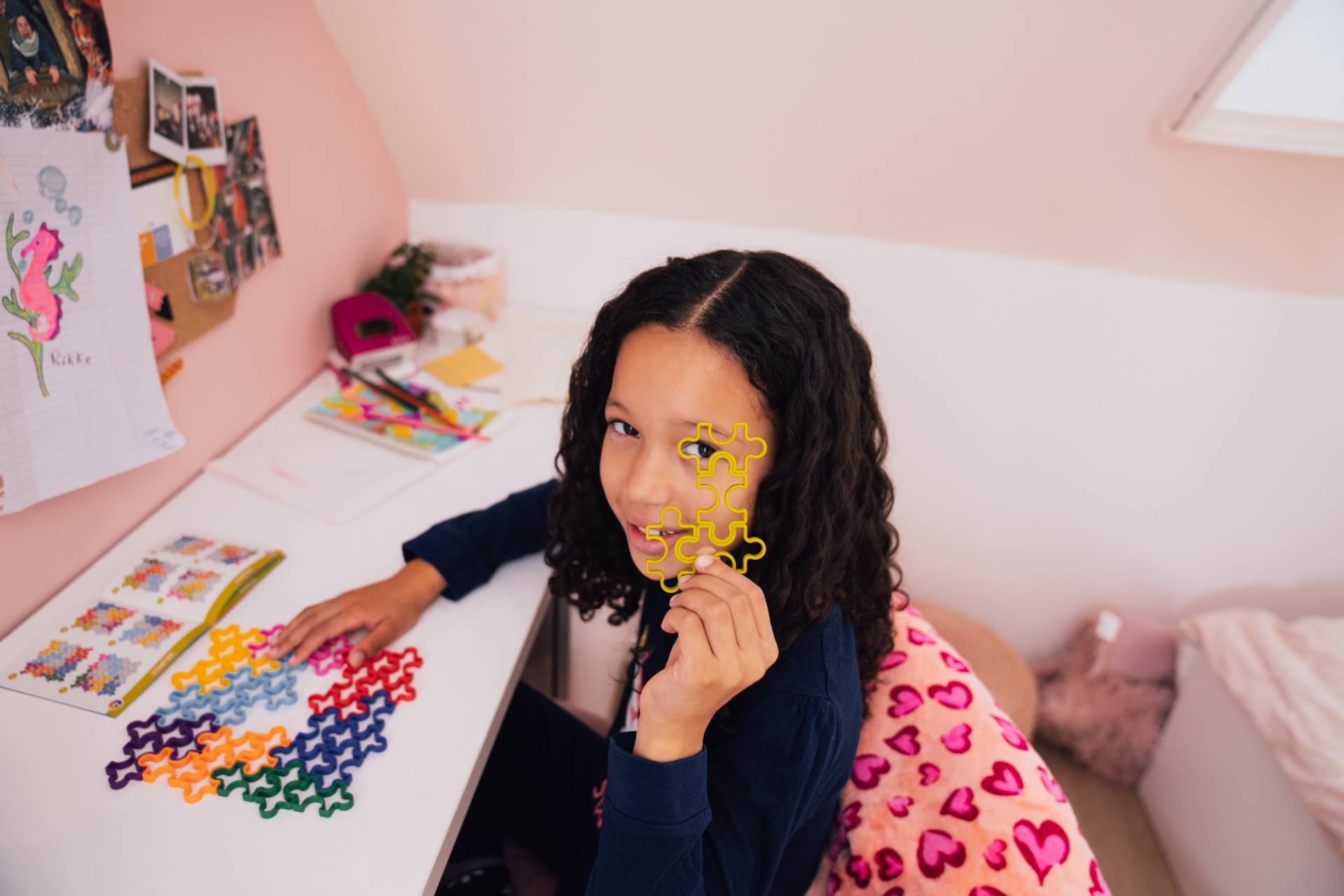 Menina a brincar com peças de puzzle coloridas numa mesa branca