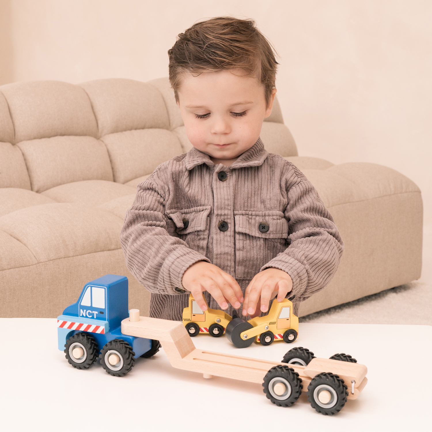 Criança a brincar com camião e máquinas de construção de madeira