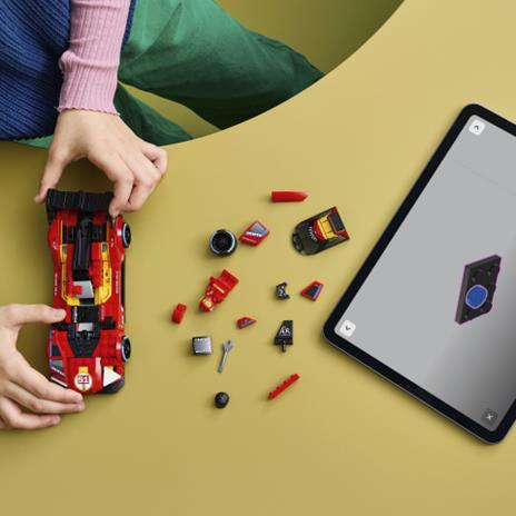 Mãos de criança a montar carro de corrida de construção vermelho com peças soltas ao lado e tablet com modelo 3D do carro.