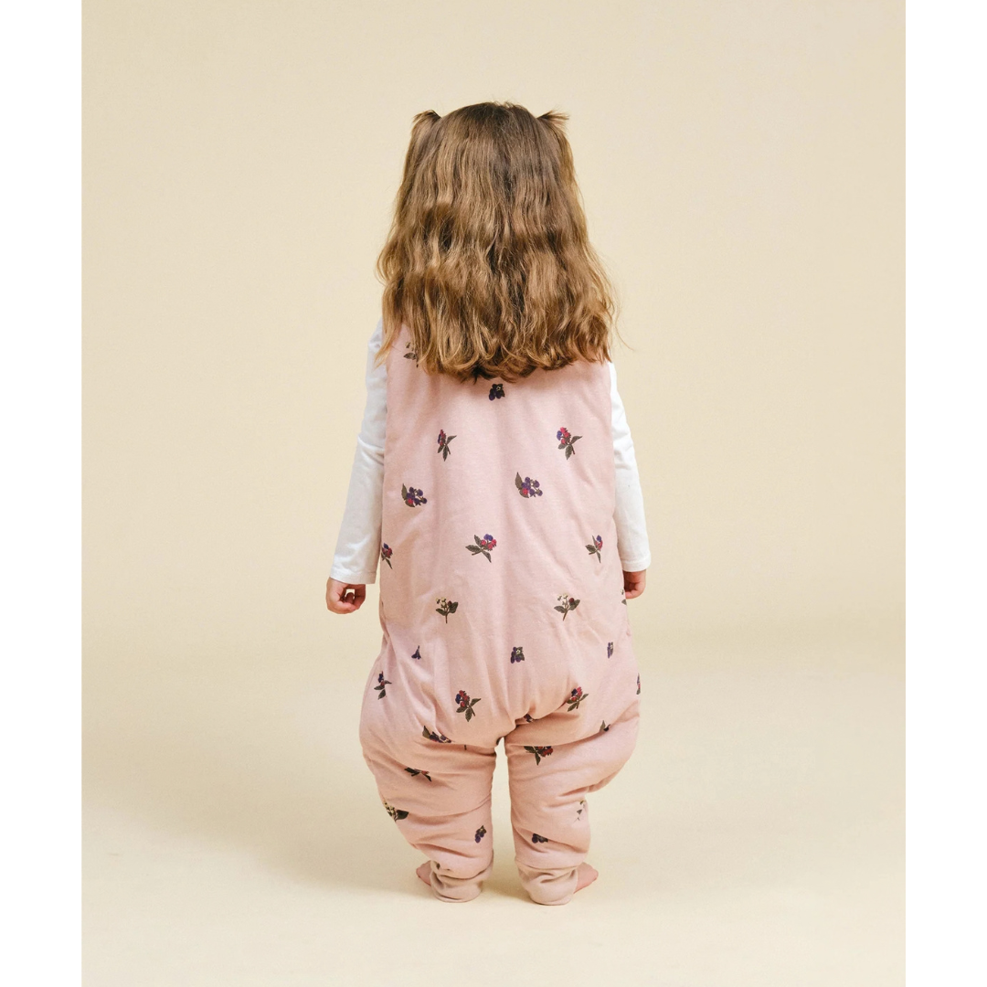 Criança de costas com roupa de bebê rosa com flores