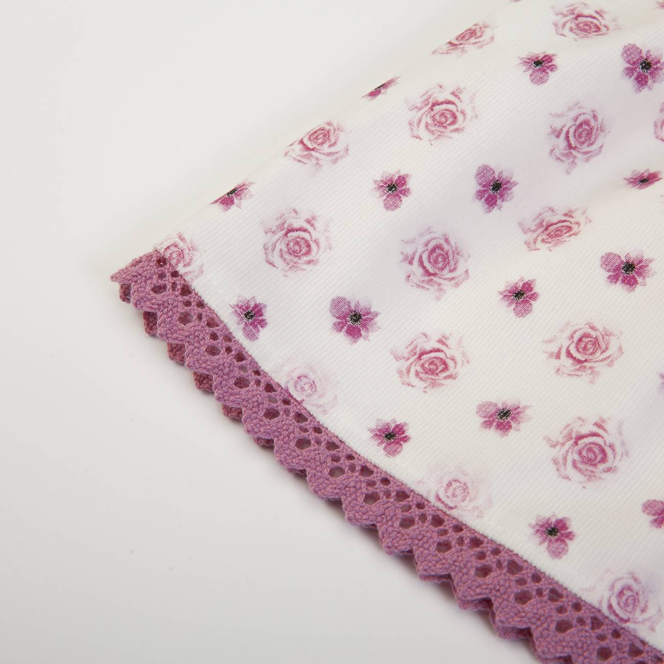Pano branco com flores cor-de-rosa e lilás e borda de renda lilás