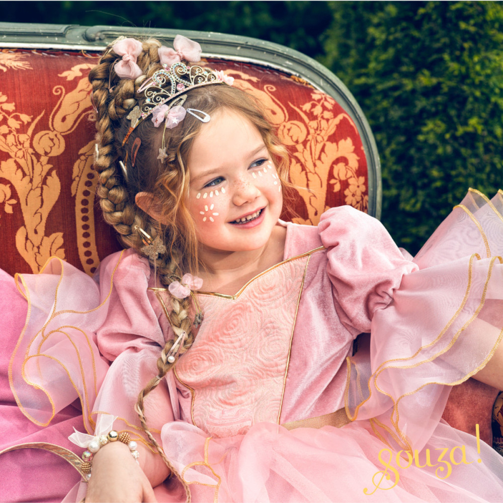 Menina com vestido cor-de-rosa e tiara sentada numa cadeira vermelha com padrão floral