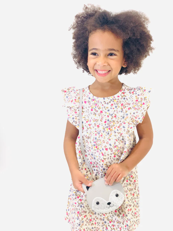 Menina com vestido floral branco e mala cinzenta de raposa