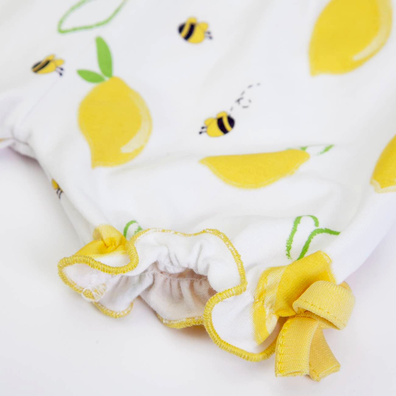 pano branco com padrão de limões e abelhas, borda com elástico e laço amarelo