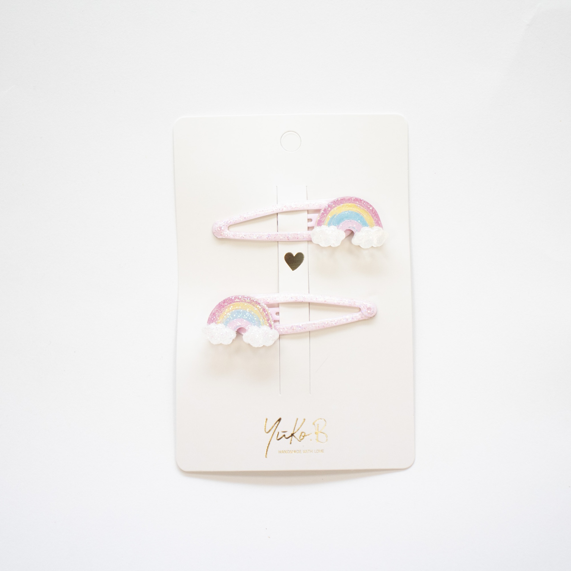 Par de molas de cabelo cor-de-rosa com arco-íris colorido pastel em cartão branco