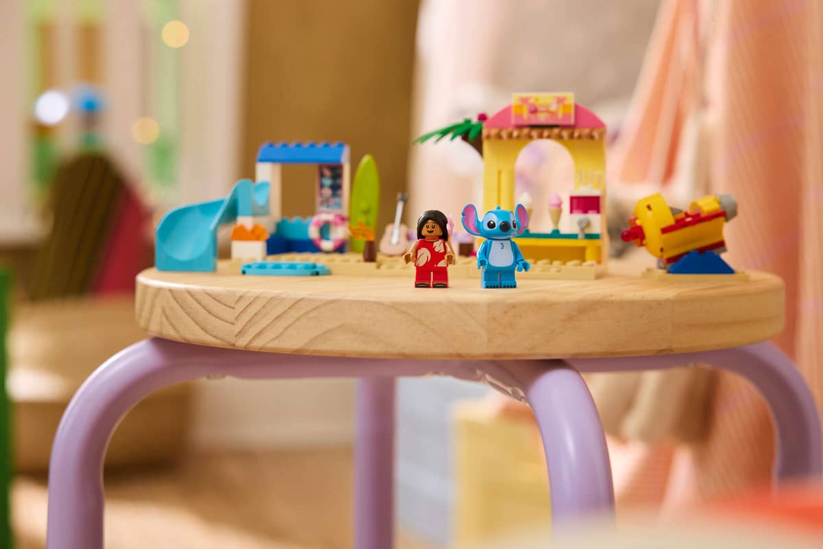 Brinquedo de construção tipo LEGO com personagens e elementos de praia sobre mesa redonda de madeira