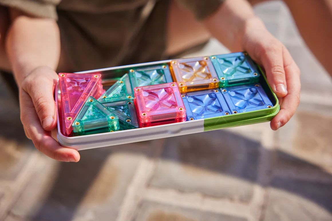 Jogo de construção magnético com peças coloridas sobre base branca e verde