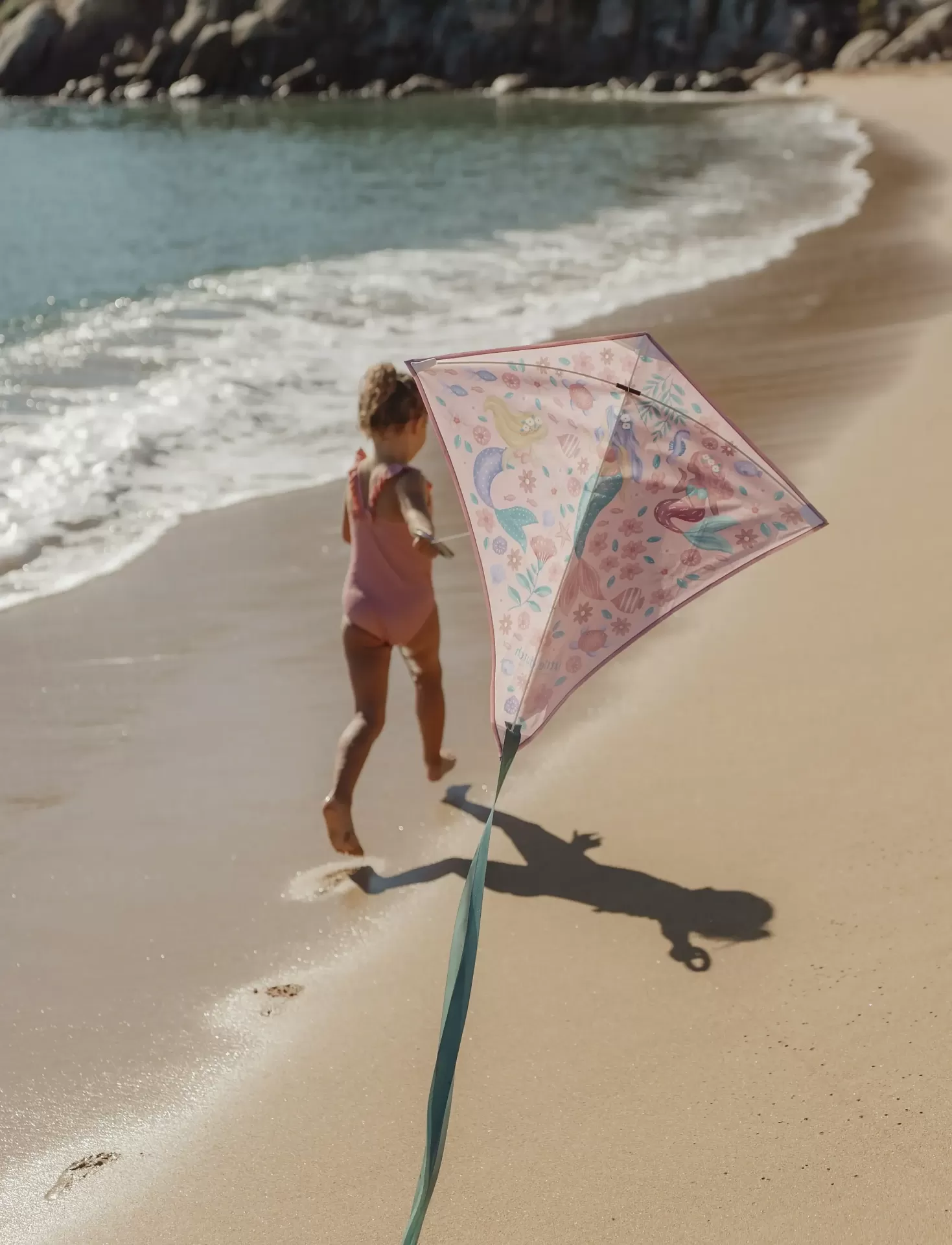 Pipa infantil colorida com padrões de sereias na praia