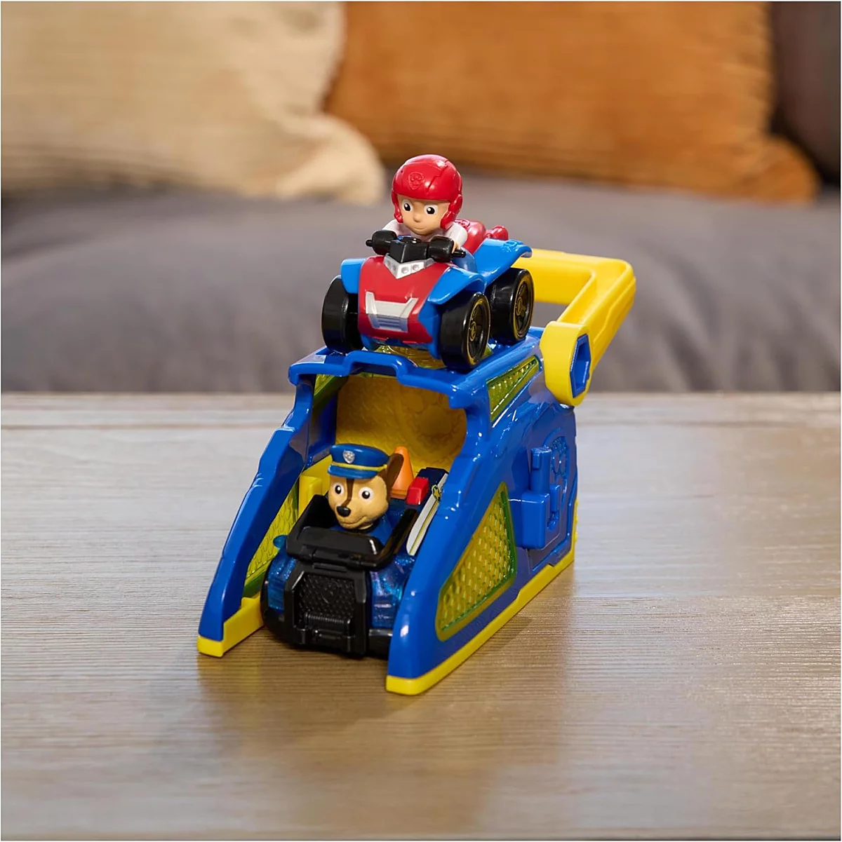 Brinquedo infantil com figuras e veículo colorido sobre mesa de madeira