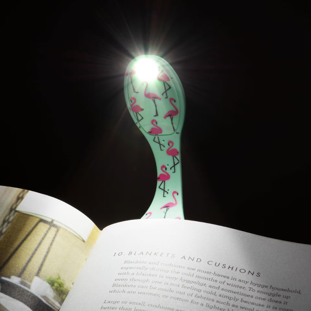 Lâmpada de leitura com padrão de flamingos a iluminar página de livro