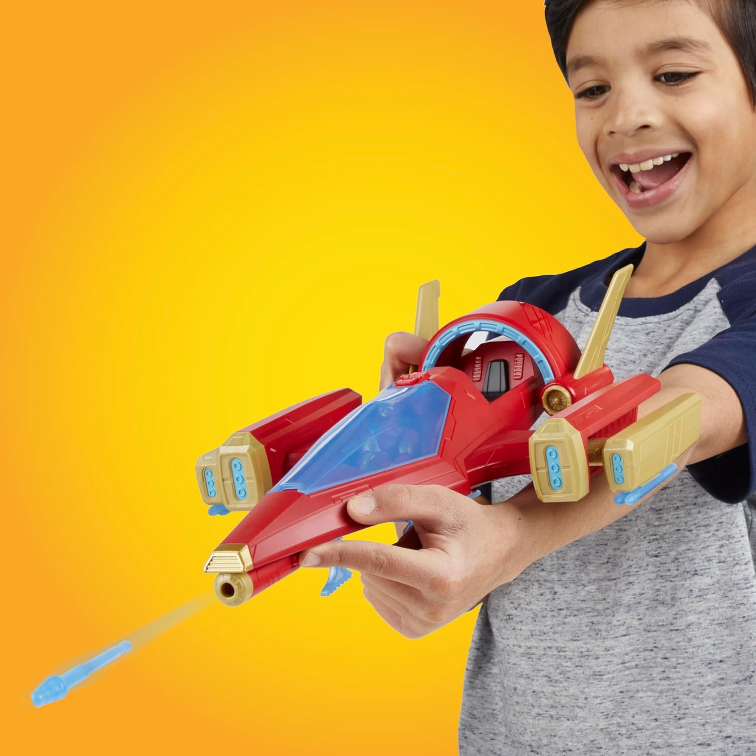 Criança a brincar com avião espacial de brinquedo vermelho e dourado em fundo laranja
