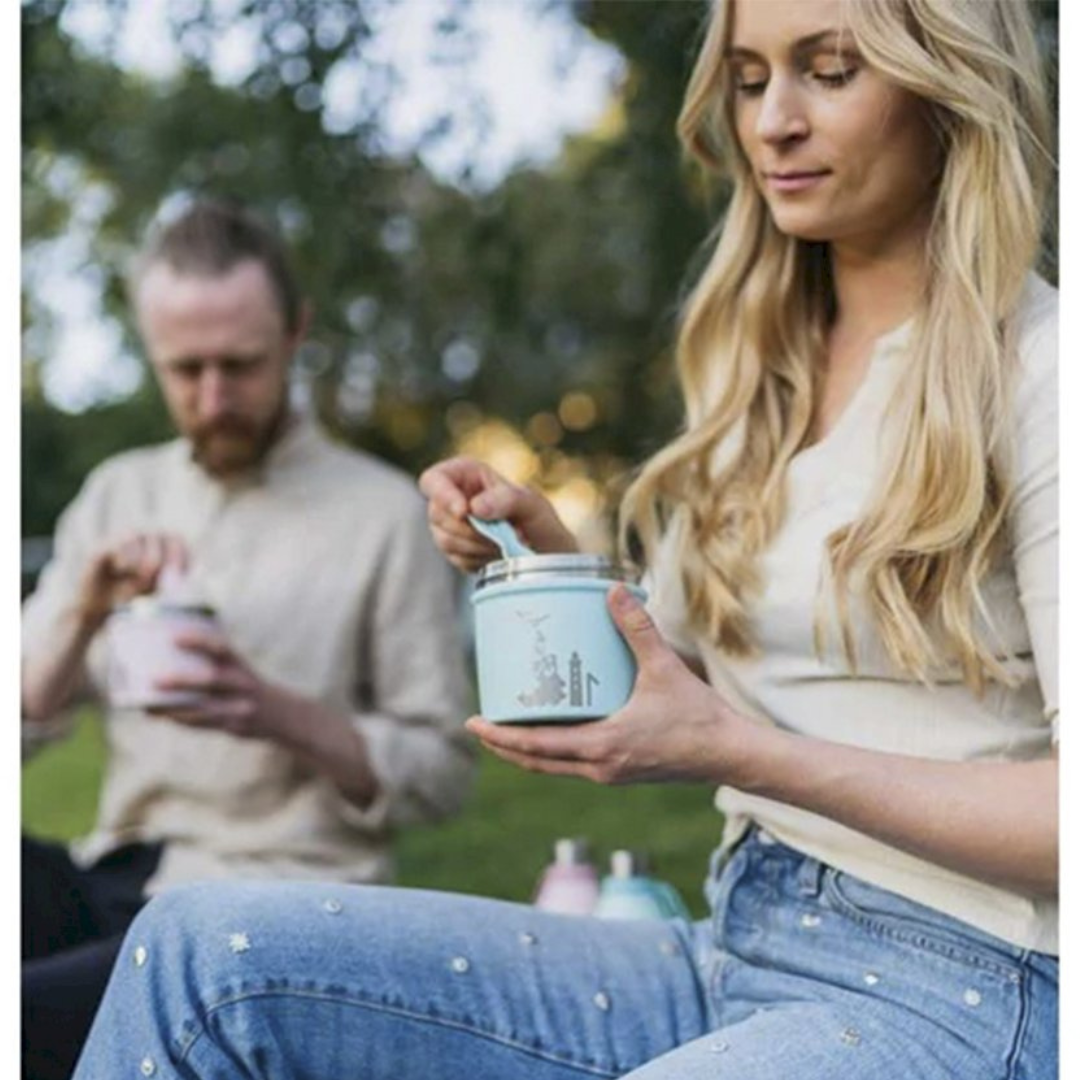 Dois adultos ao ar livre com recipientes azuis e colheres