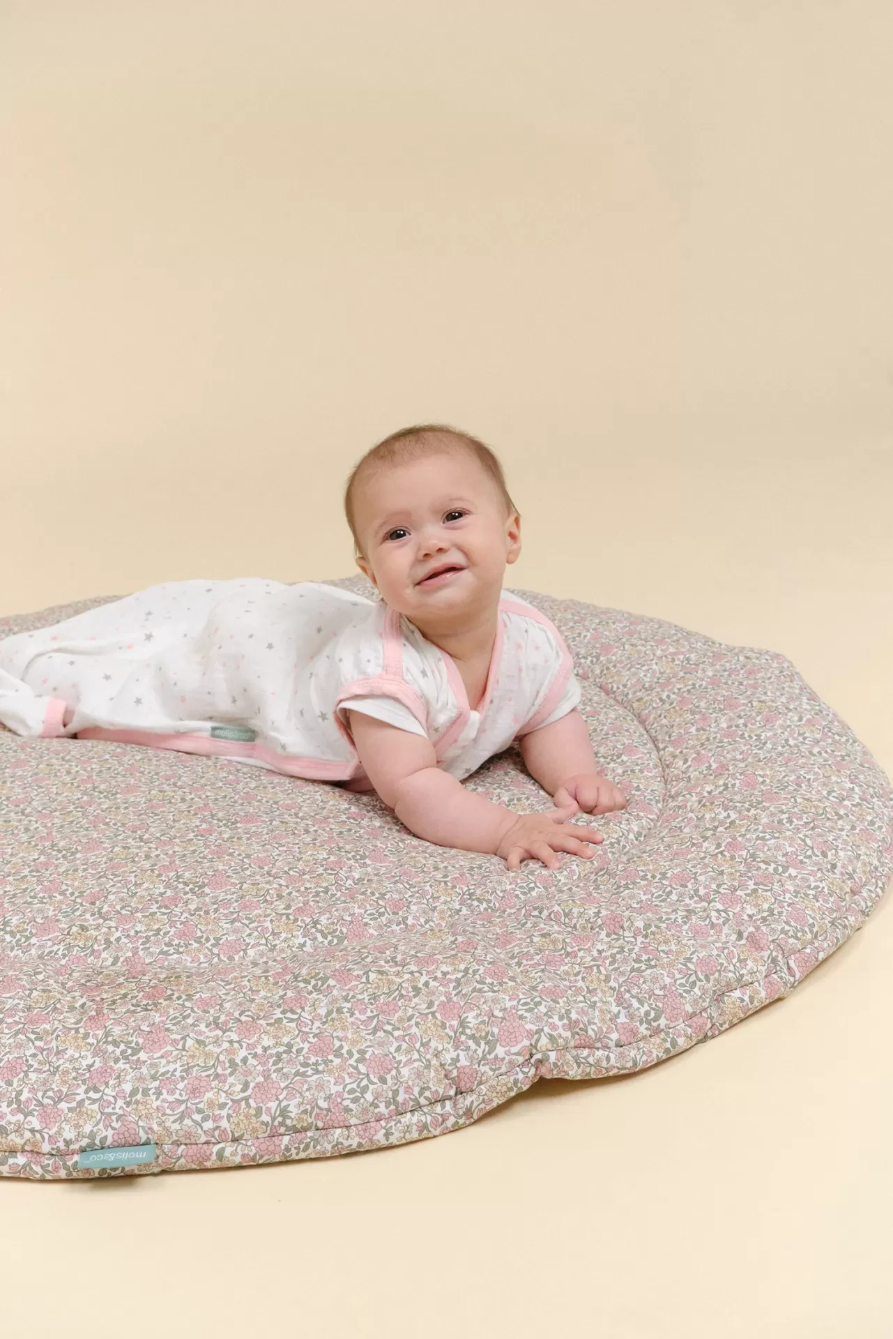 Bebé deitado sobre almofada floral rosa redonda