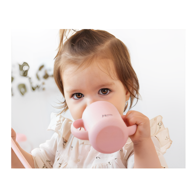 Criança a beber de chávena rosa de silicone com pegas