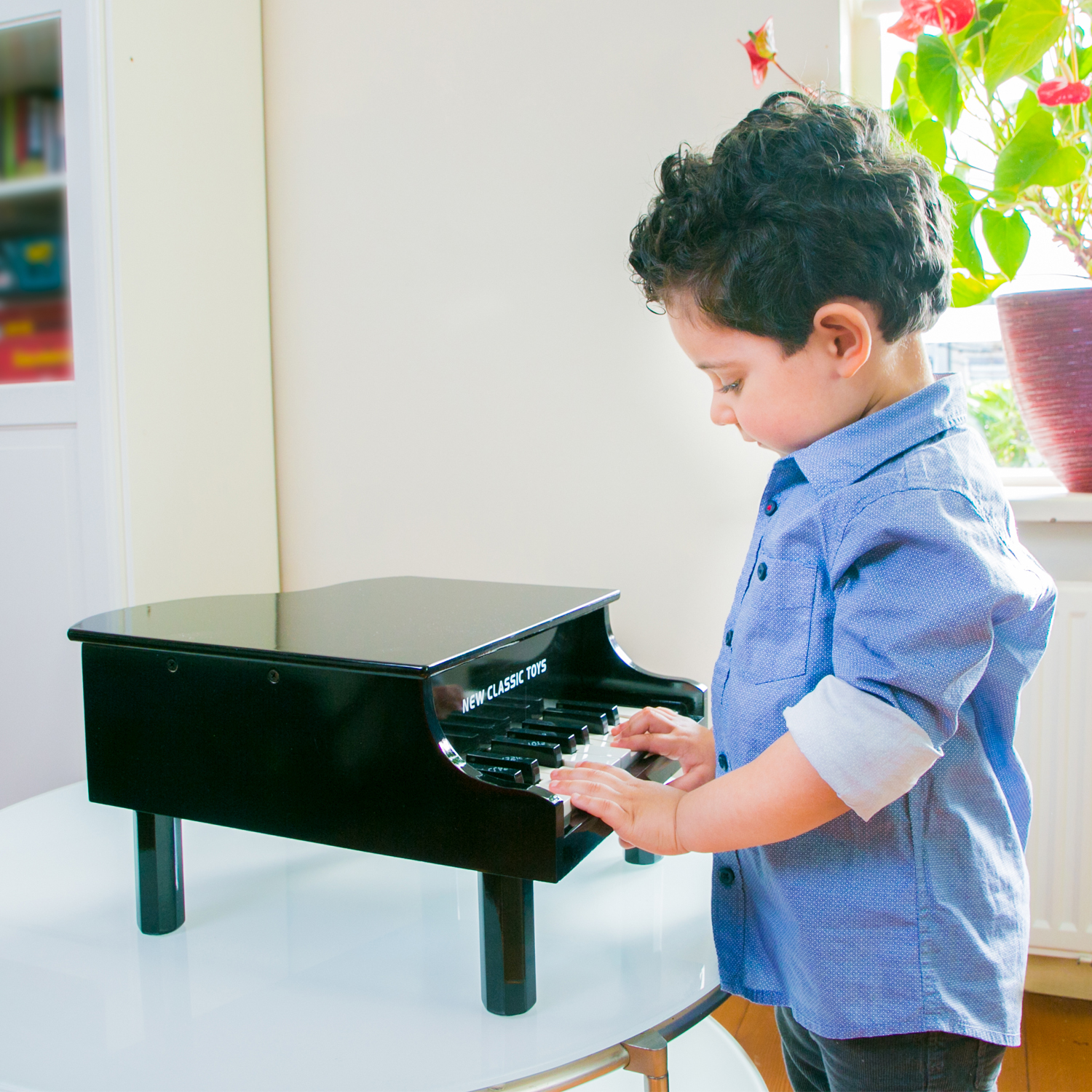 Criança a tocar piano de brinquedo preto num ambiente interior