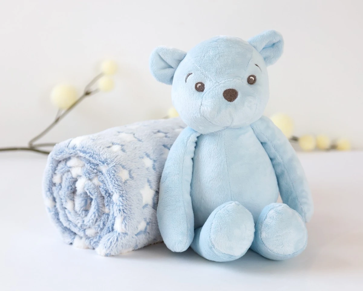 Urso de peluche azul claro e manta azul claro com estrelas brancas
