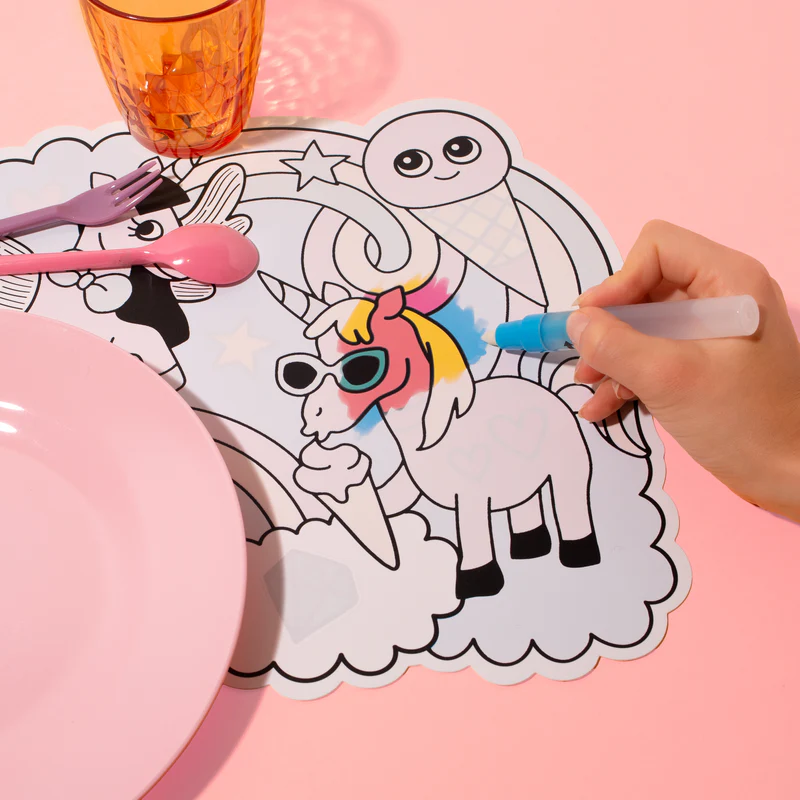 Guardanapo ou base para prato para colorir com unicórnio, sorvete e desenhos fantásticos numa mesa rosa