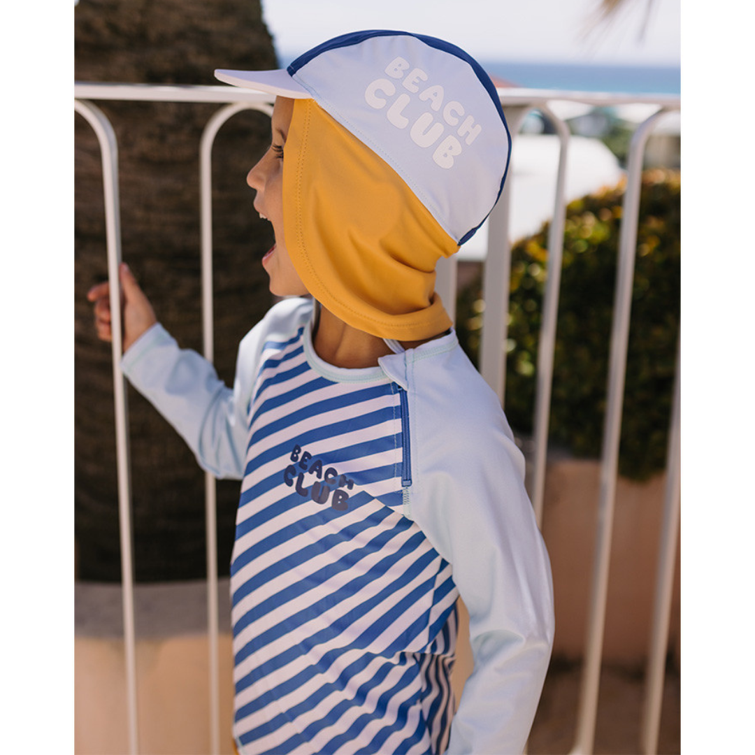 Criança com roupa de proteção solar e chapéu colorido com texto Beach Club