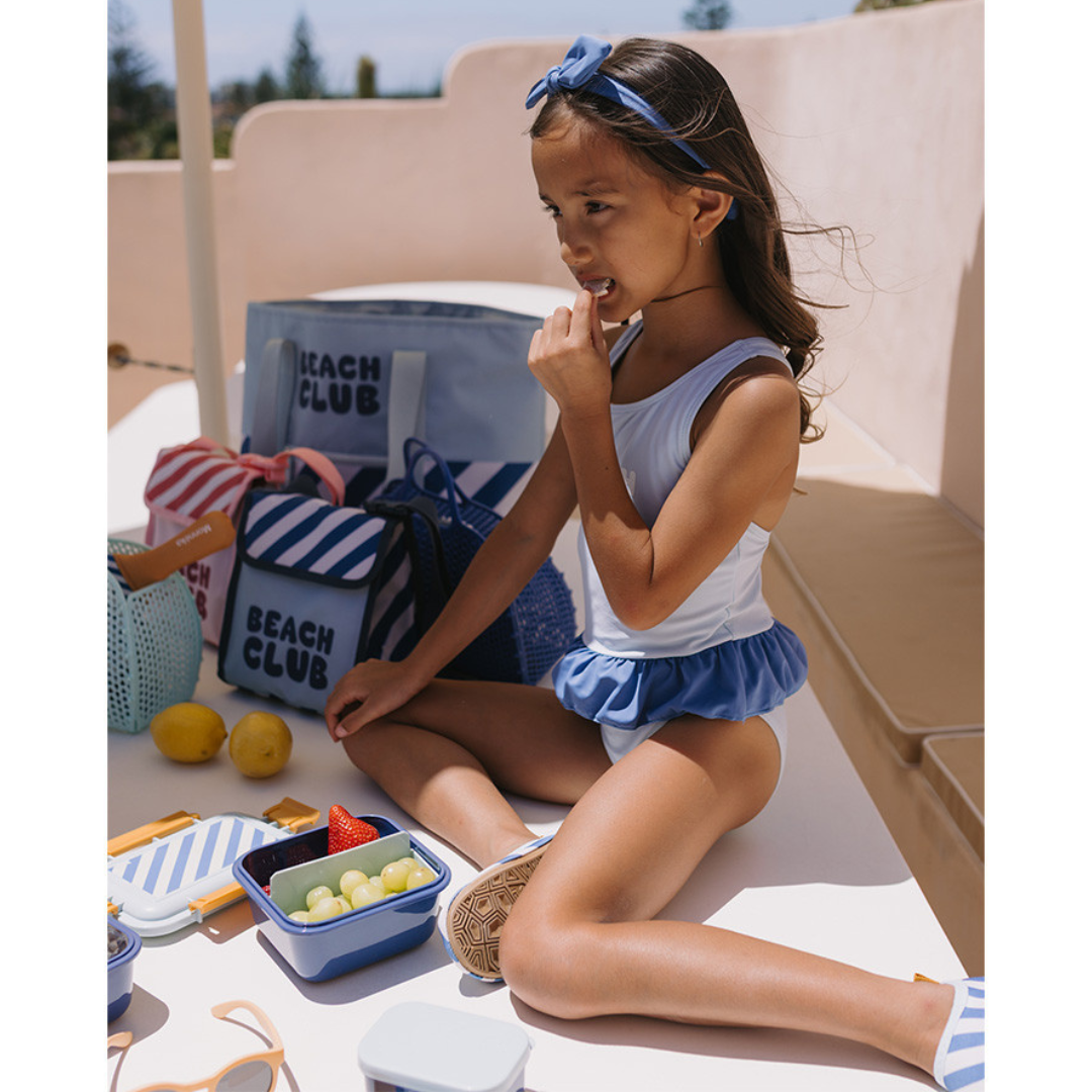 Criança com fato de banho branco e azul e acessórios azul e branco com bolsas BEACH CLUB