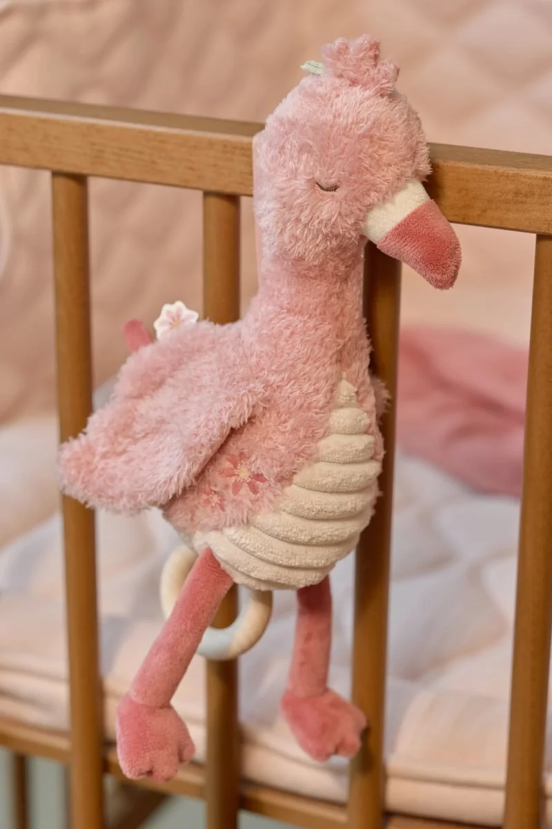 Peluche rosa de pássaro pendurado numa grade de berço